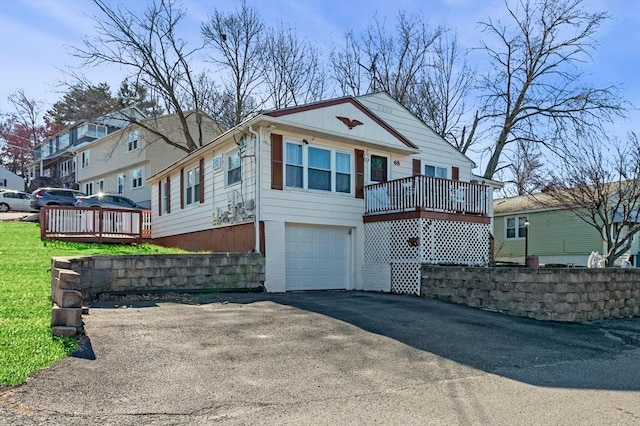view of front of property with aphalt driveway, a wooden deck, and an attached garage
