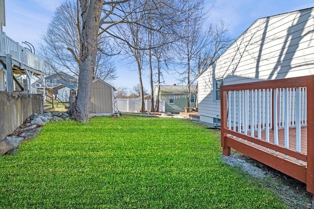 view of yard with a storage shed, fence, a deck, and an outdoor structure