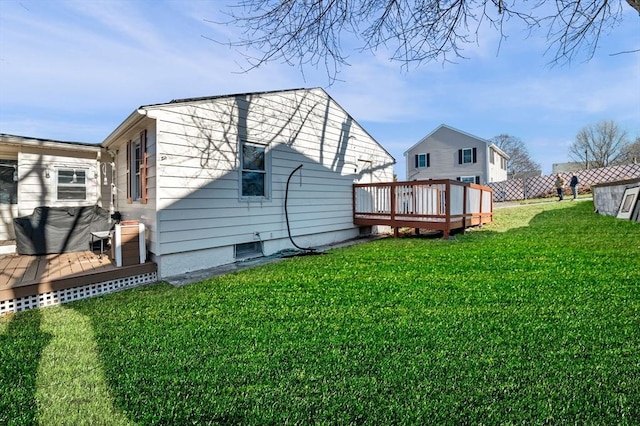 back of house with fence, a deck, and a lawn