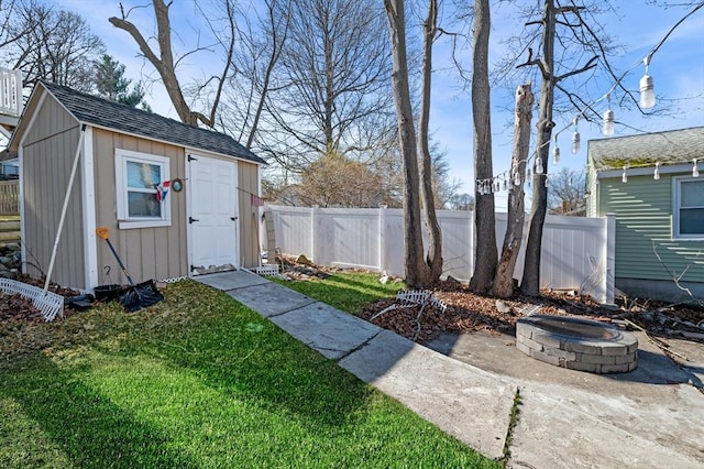 view of yard featuring a fenced backyard, an outdoor structure, a fire pit, and a storage unit
