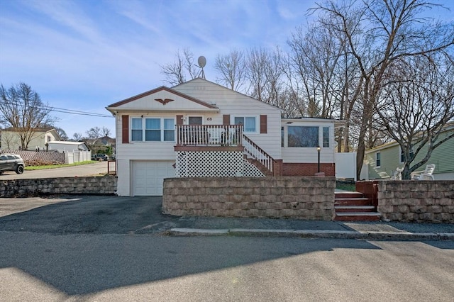 view of front facade featuring aphalt driveway, a garage, fence, and stairway
