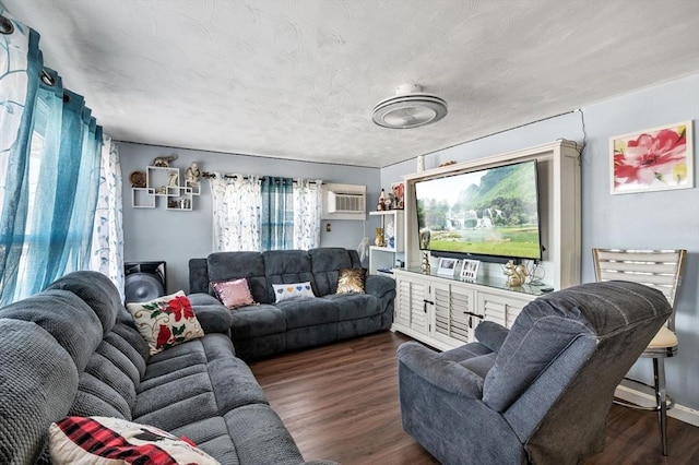 living area with a textured ceiling, wood finished floors, and a wall unit AC