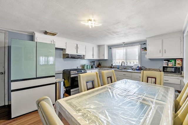 kitchen with stainless steel range with gas cooktop, black microwave, visible vents, white cabinets, and under cabinet range hood
