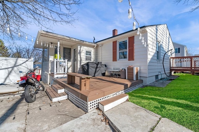 back of house with a yard, a wooden deck, and a chimney