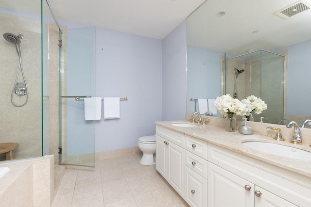 bathroom featuring toilet, vanity, tile patterned flooring, and a shower with door