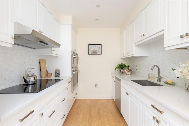 kitchen with appliances with stainless steel finishes, white cabinetry, tasteful backsplash, and sink