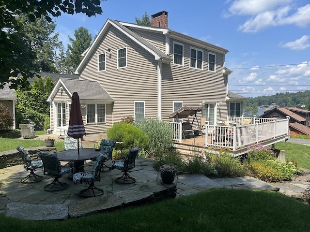 back of house with a deck and a patio