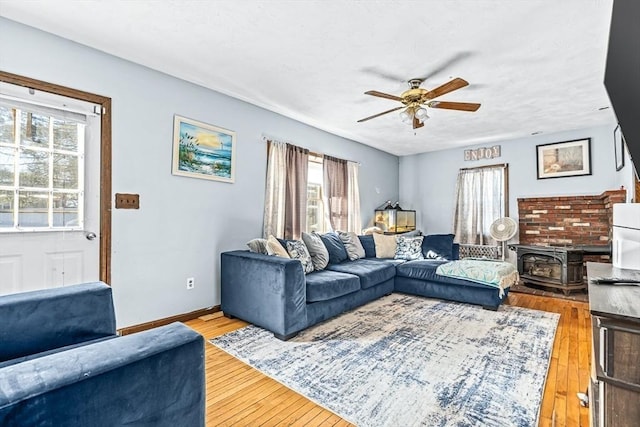 living room with hardwood / wood-style flooring, ceiling fan, and a wood stove