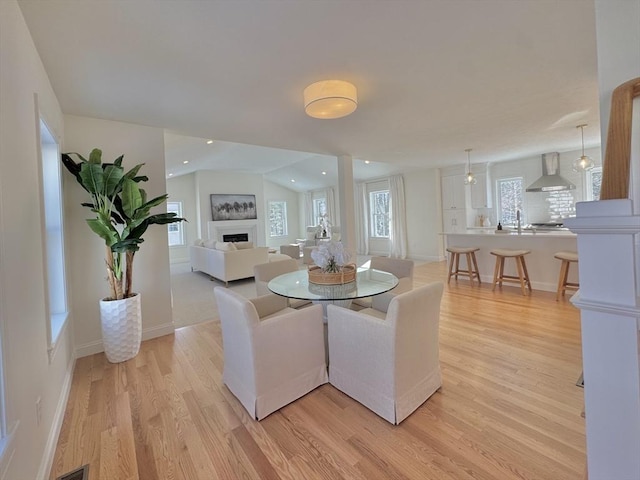 dining space with lofted ceiling, sink, and light hardwood / wood-style floors