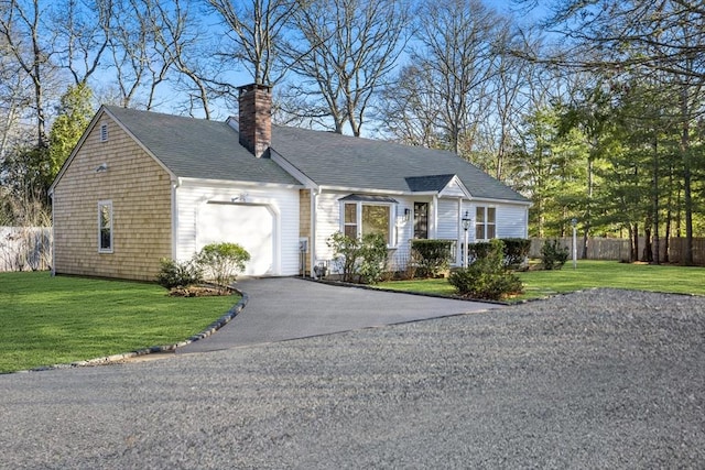 view of front facade featuring a front lawn, an attached garage, fence, and aphalt driveway