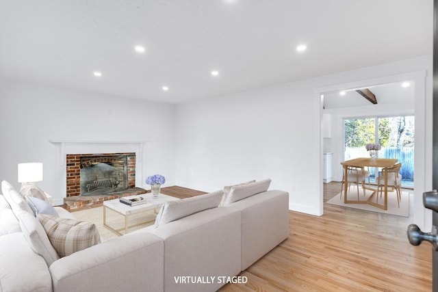 living area with recessed lighting, baseboards, a brick fireplace, and light wood-style flooring