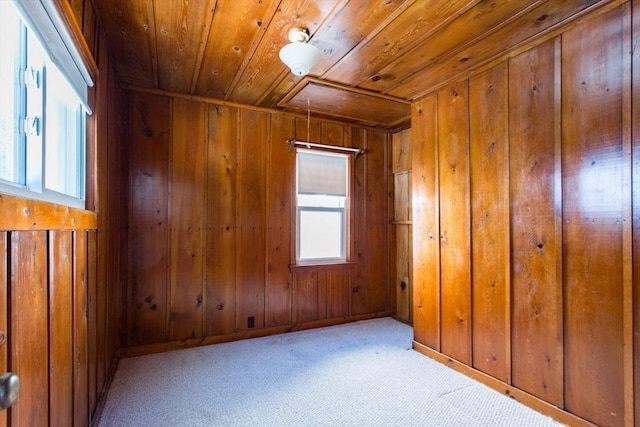 carpeted spare room with wooden walls and wooden ceiling