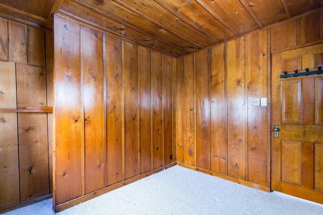 carpeted spare room featuring wood ceiling and wooden walls