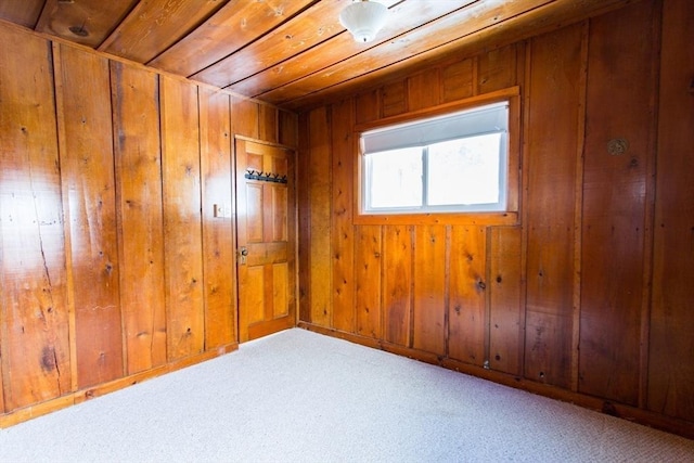 carpeted empty room with wooden ceiling and wooden walls