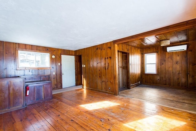 interior space featuring hardwood / wood-style flooring, wooden walls, a wall mounted AC, and baseboard heating