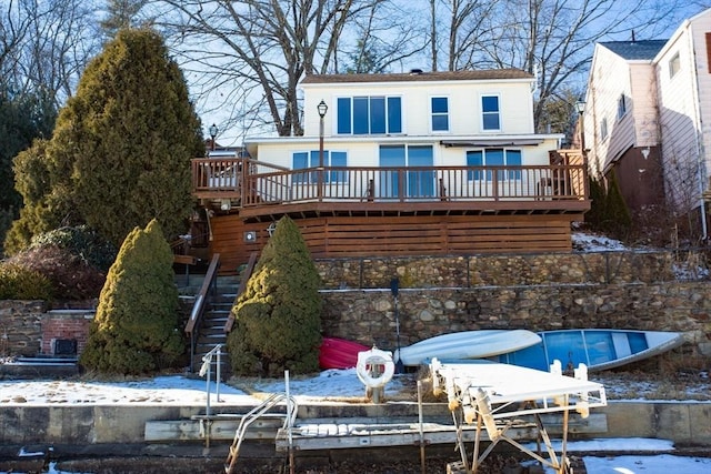 snow covered rear of property with a wooden deck