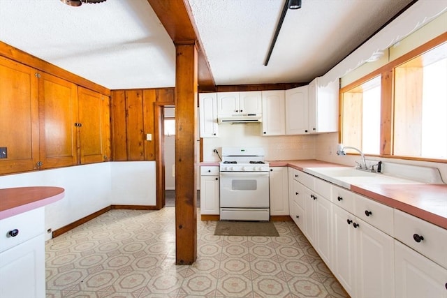 kitchen with sink, white cabinets, backsplash, gas range gas stove, and a textured ceiling