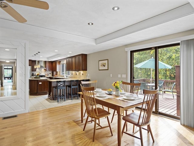 dining area with light wood-type flooring, a raised ceiling, visible vents, and recessed lighting