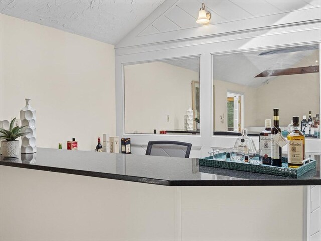 kitchen featuring dark countertops, vaulted ceiling, and a textured ceiling