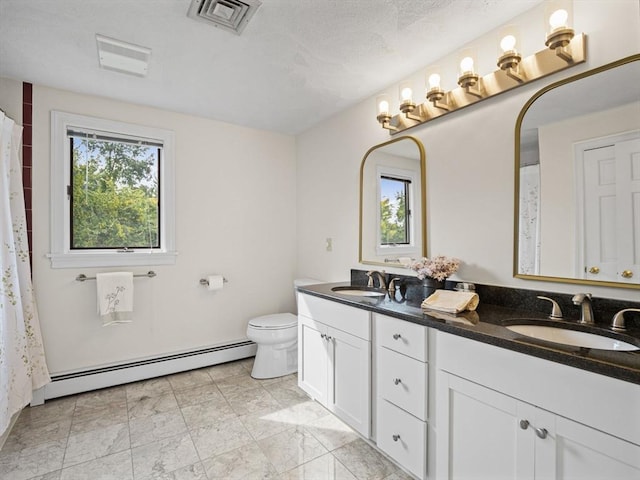 bathroom featuring visible vents, a sink, baseboard heating, and double vanity