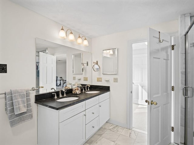 full bathroom with double vanity, marble finish floor, baseboards, and a sink