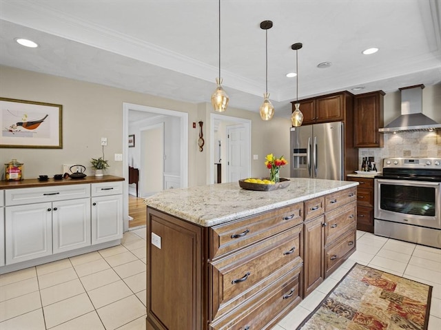 kitchen featuring light tile patterned floors, stainless steel appliances, hanging light fixtures, wall chimney exhaust hood, and tasteful backsplash