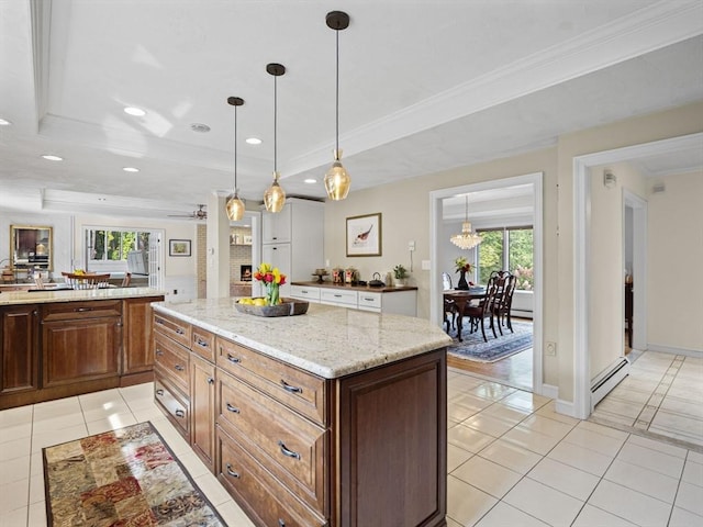 kitchen with hanging light fixtures, a tray ceiling, light tile patterned flooring, and a kitchen island