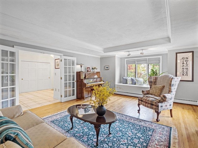 living room featuring a baseboard radiator, a raised ceiling, and wood finished floors