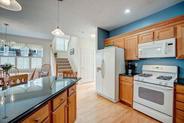 kitchen with brown cabinets, white appliances, light wood-style floors, and pendant lighting