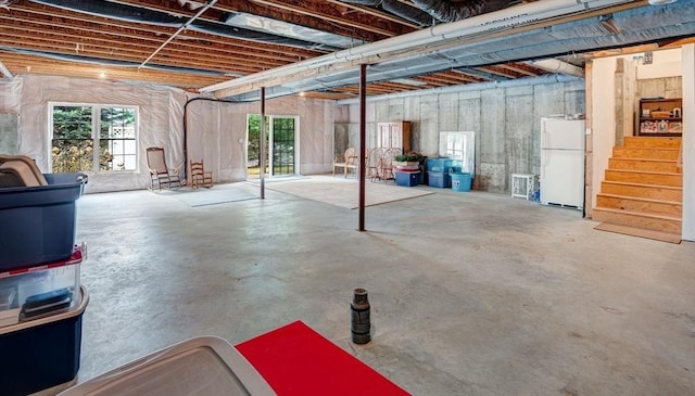 basement featuring freestanding refrigerator, stairway, and a wealth of natural light
