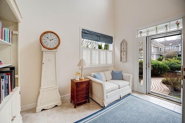 living area featuring a towering ceiling, baseboards, and light tile patterned floors