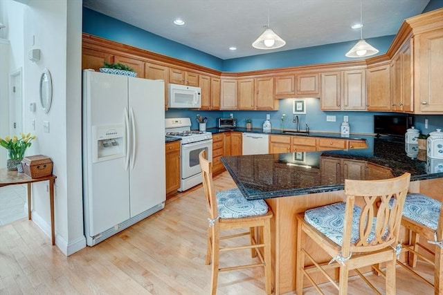 kitchen featuring a sink, light wood-style floors, white appliances, pendant lighting, and a peninsula