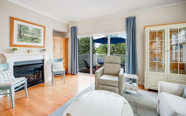 living area with a glass covered fireplace, wood finished floors, and crown molding