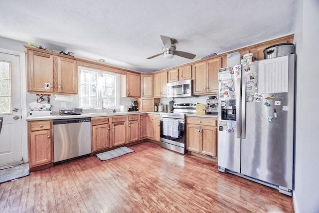 kitchen featuring stainless steel appliances, wood-type flooring, sink, and ceiling fan