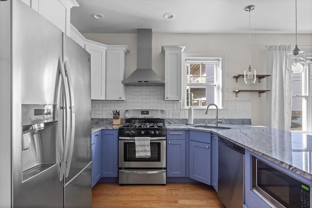 kitchen with white cabinetry, sink, wall chimney exhaust hood, blue cabinets, and appliances with stainless steel finishes