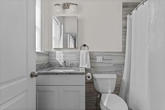 bathroom with vanity, toilet, and tile walls