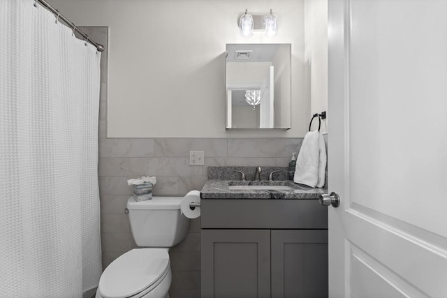 bathroom with vanity, toilet, tile walls, and curtained shower