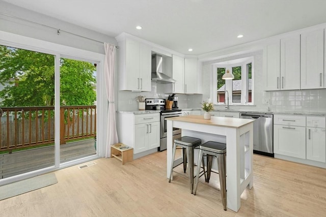 21 Milton Rd, Quincy, MA 02171 - kitchen featuring stainless steel appliances, wall chimney range hood, a center island, healthy amount of natural light, and recessed lighting