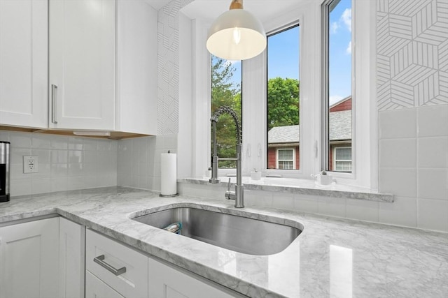 21 Milton Rd, Quincy, MA 02171 - kitchen featuring a sink, white cabinetry, light stone countertops, backsplash, and pendant lighting