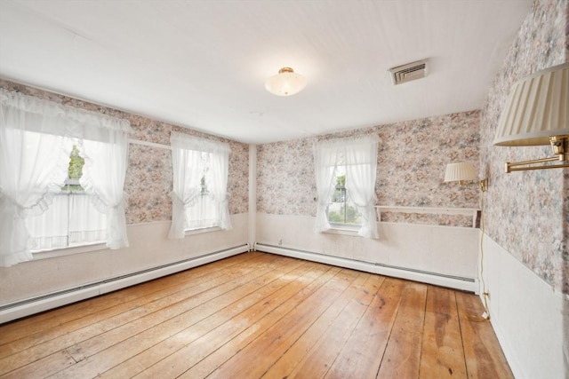 197-199 Main St, Chelmsford, MA 01863 - empty room with wallpapered walls, wood-type flooring, baseboard heating, and wainscoting