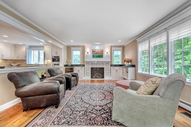 24 Cory Ln, Reading, MA 01867 - living area featuring light wood-style floors, crown molding, a tiled fireplace, beverage cooler, and recessed lighting