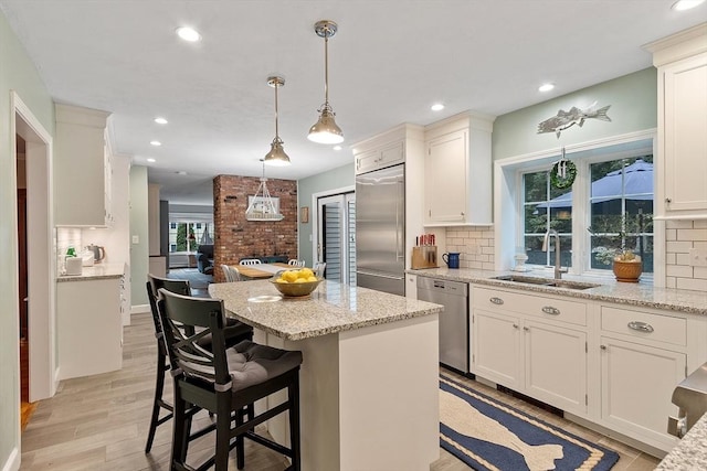 15 Saxon Ln, Shrewsbury, MA 01545 - kitchen featuring stainless steel appliances, a center island, light wood-style flooring, decorative backsplash, and light stone countertops