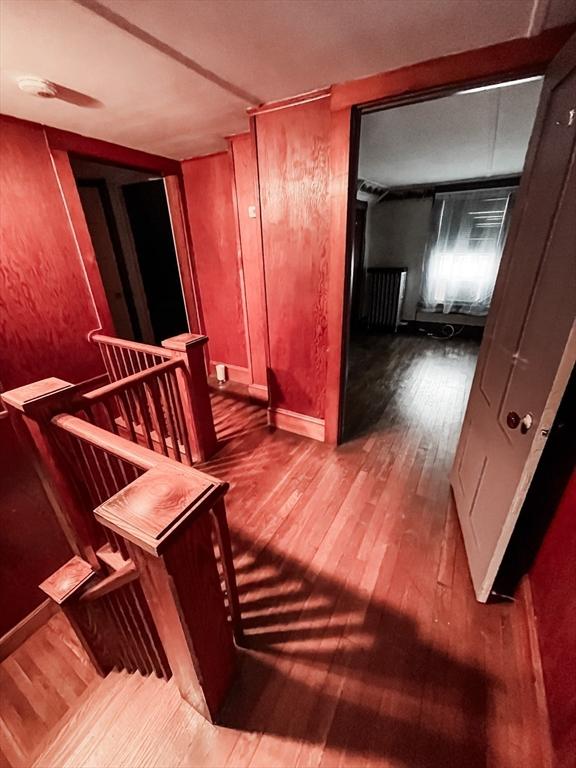 hallway with wood-type flooring and an upstairs landing