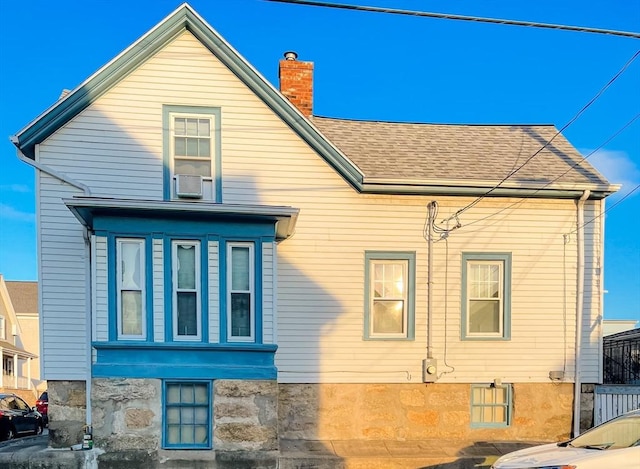 rear view of property with a shingled roof and a chimney