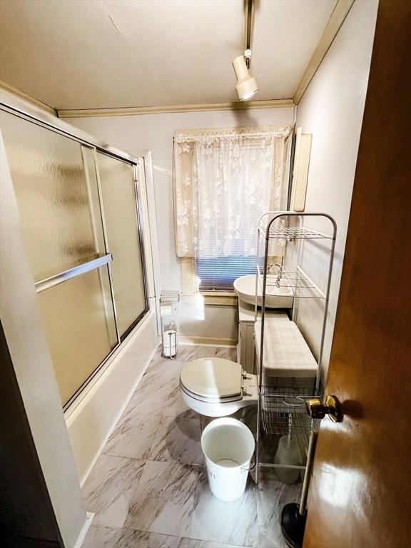 full bathroom with marble finish floor, enclosed tub / shower combo, crown molding, and toilet