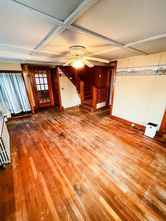 unfurnished living room with stairs, coffered ceiling, wood finished floors, and a ceiling fan