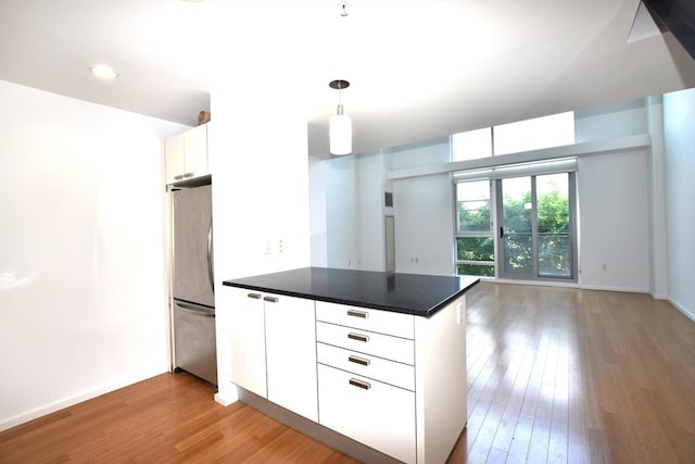 1 Earhart St Unit 320, Cambridge, MA 02141 - kitchen featuring freestanding refrigerator, a peninsula, light wood-style flooring, white cabinetry, and dark countertops