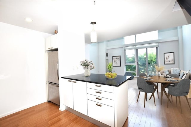 1 Earhart St Unit 320, Cambridge, MA 02141 - kitchen featuring freestanding refrigerator, a peninsula, light wood-style flooring, open floor plan, and dark countertops