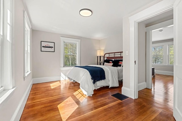 bedroom featuring baseboards, hardwood / wood-style floors, and visible vents