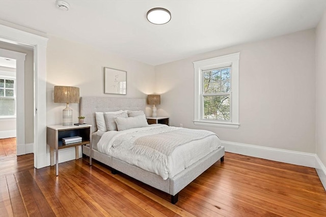 bedroom featuring baseboards, hardwood / wood-style floors, and multiple windows